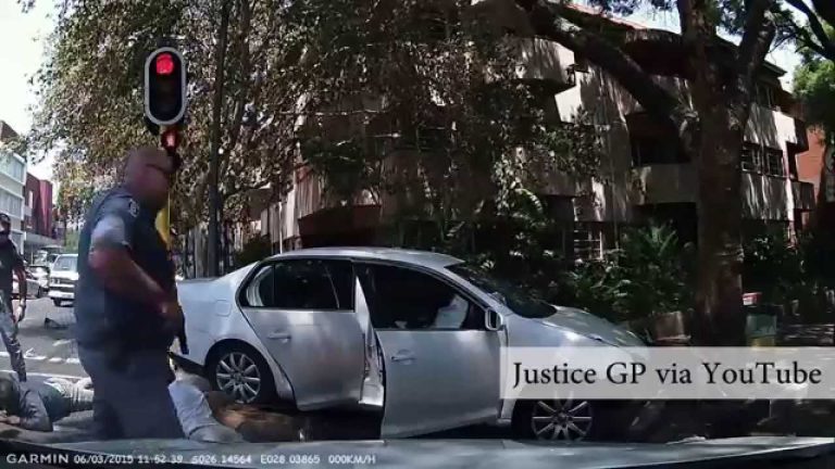 Police arrest beside silver car at traffic light.