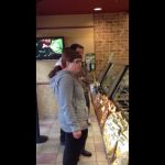 People waiting in line at a sandwich shop.