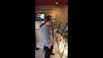 People waiting in line at a sandwich shop.