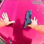 Person securing handgun on red car hood.
