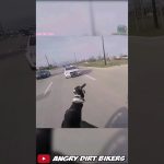 Motorcyclist gestures at police car on road.