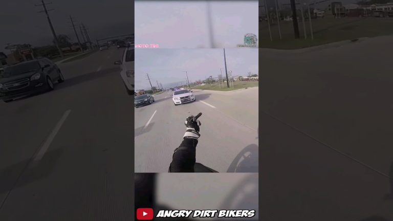 Motorcyclist gestures at police car on road.