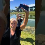 People holding phones by a pond