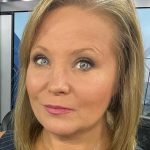 Person in news studio setting, close-up view.