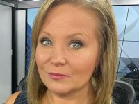 Person in news studio setting, close-up view.