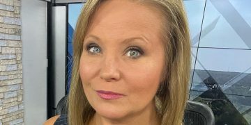 Person in news studio setting, close-up view.