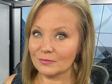 Person in news studio setting, close-up view.