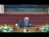 Man speaking at a church podium with flowers.
