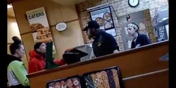 Subway employees interacting with customers at the counter.