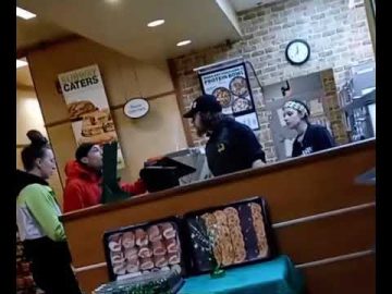 Subway employees interacting with customers at the counter.