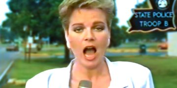 Reporter in front of police station sign