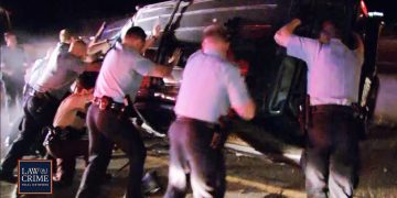Police officers flip overturned car during night operation.