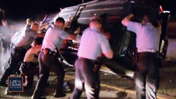 Police officers flip overturned car during night operation.
