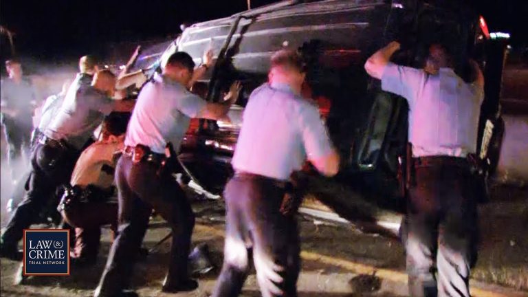 Police officers flip overturned car during night operation.