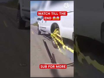 Truck wheel tangled in yellow tape on road.