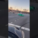 Green car drifting on a wide intersection road.