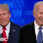 Two men in suits on TV debate screen.