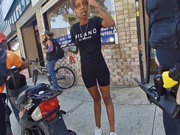 People talking and standing near a scooter on sidewalk.