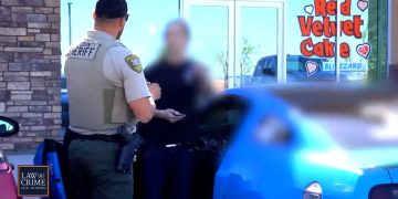 Sheriff talking to person by blue car