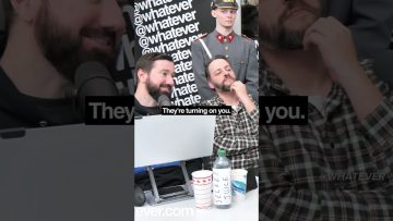 Two men with microphones and soldier prop behind.