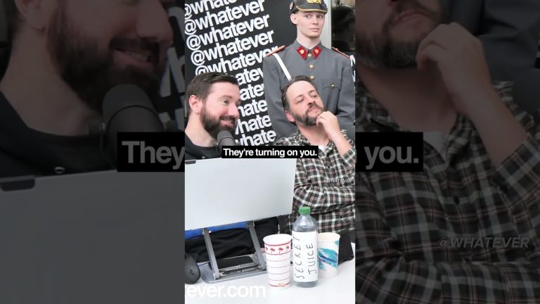 Two men with microphones and soldier prop behind.