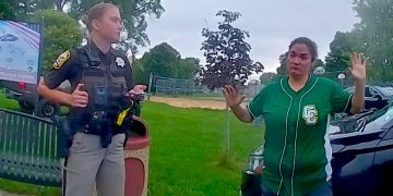 Police officer interacts with person in green shirt.