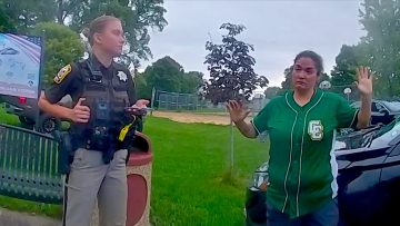 Police officer interacts with person in green shirt.