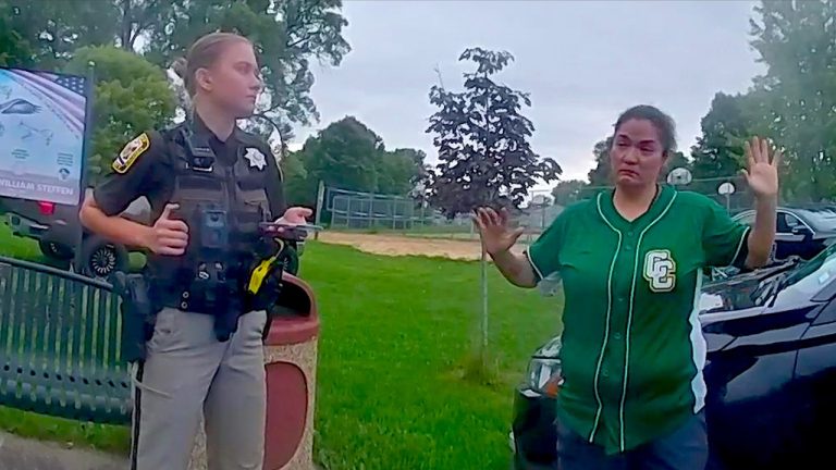Police officer interacts with person in green shirt.