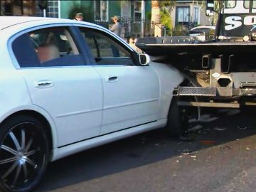White car rear-ended by tow truck.