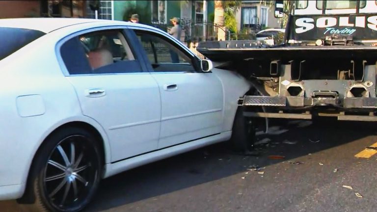 White car rear-ended by tow truck.