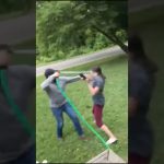 Two people playing with water hose outdoors.