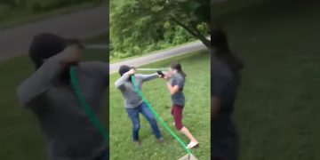 Two people playing with water hose outdoors.