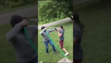 Two people playing with water hose outdoors.