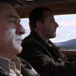 Two men driving through scenic mountains