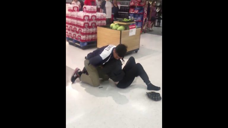 Security tackle in supermarket near bottled drinks display.