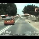 Car crossing railway tracks under lowering barriers.