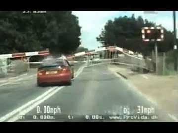 Car crossing railway tracks under lowering barriers.