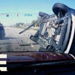 Two-car collision at intersection with flipped vehicle.