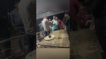 Group of men arguing near a table at night.