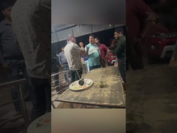 Group of men arguing near a table at night.