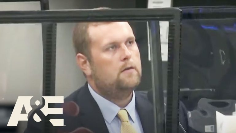 Man in suit behind glass at a desk.