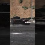Truck drifting on wet road in city scene.