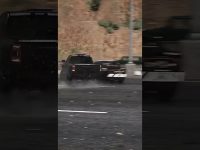 Truck drifting on wet road in city scene.