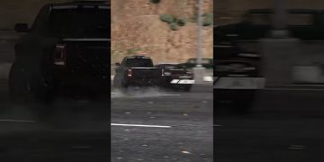 Truck drifting on wet road in city scene.