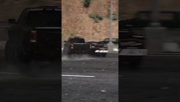 Truck drifting on wet road in city scene.