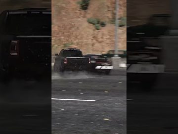 Truck drifting on wet road in city scene.