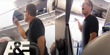 Passenger arguing on airplane near luggage compartment.