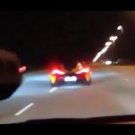 Sports car driving fast on highway at night.