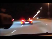 Sports car driving fast on highway at night.