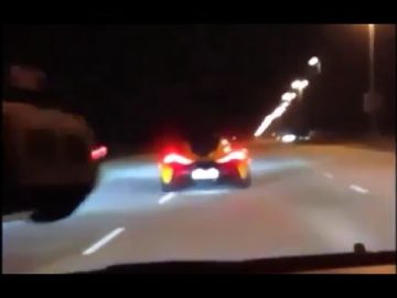Sports car driving fast on highway at night.